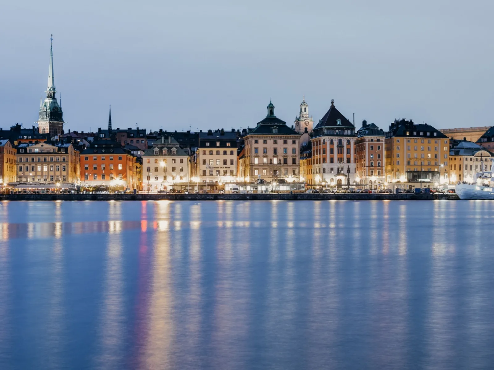 Oplyste bygninger langs en havnefront i skumringen