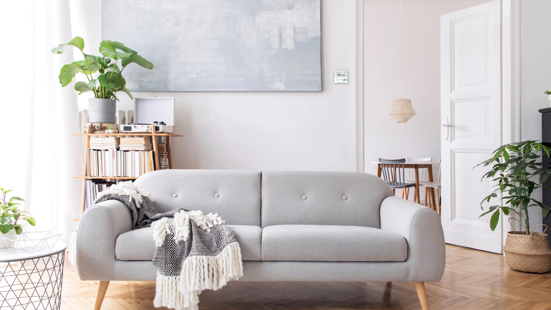 Lys stue med grå sofa, planter og en dør ud til spisestuen